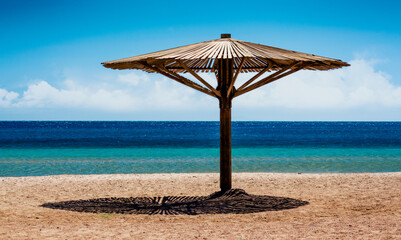wooden beach umbrella on the shore without people of the Red Sea in Egypt