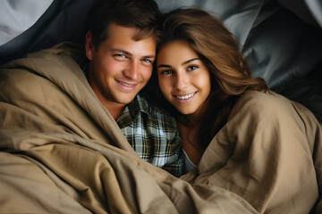 Young couple lying under blanket in bedroom, top view - obrazy, fototapety, plakaty