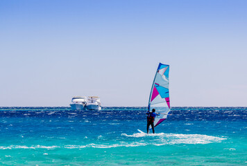 surfer rides in the Red Sea against the backdrop of two ships in Egypt Dahab