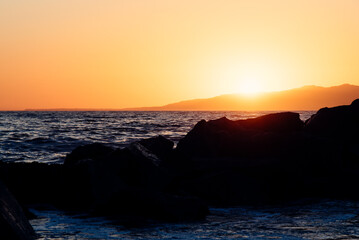 Sunset behind the rocks on the beach