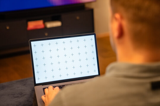 Young man holding his laptop, reading news, browsing internet or digital application, watching video, in cozy living room light