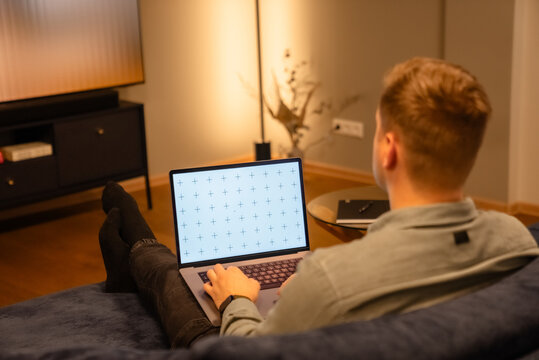 Man working, laptop in a lap, glass table, browsing computer with blank screen mock-up for your design at home office with blurry background with free space for custom text about business