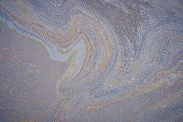 A marble texture of a rainbow spill of gasoline on a sidewalk in a puddle as a background