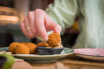 Close up of traditional Dutch bitterballen being dipped in mustard in a café restaurant