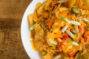 Close up of nachos with meat and cheese on a white plate on a wooden table in a café restaurant