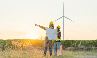 Caucasian engineer man and female engineering worker builders are looking for wind turbine blueprint drawings for wind turbine construction at a windmill field farm.