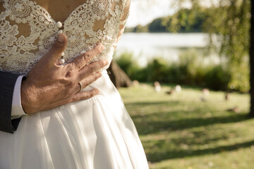 Liebevolle Gäste am Hochzeitstag Bräutigam legt der Braut die Hand auf den Rücken - 699609853