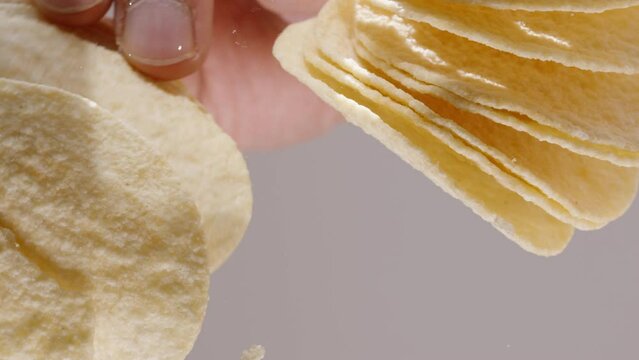 Corn chips in the shape of a saddle, view from below through a glass table. Hands want to take them but can't reach, macro.