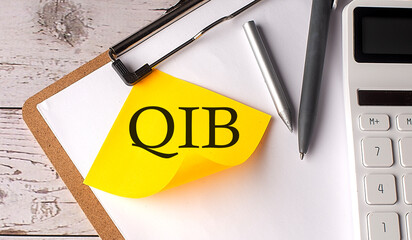 QIB word on a yellow sticky with calculator, pen and clipboard