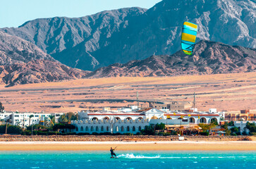 one surfer with a sail on a rocky shore and hotels in the Red Sea in Egypt - Powered by Adobe