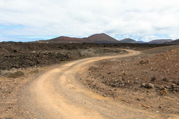 Country road in a volcanic landscape in Los Ajaches National Park near Papagayo. Playa Blanca, Lanzarote, Spain. Tourism and vacations concept. 