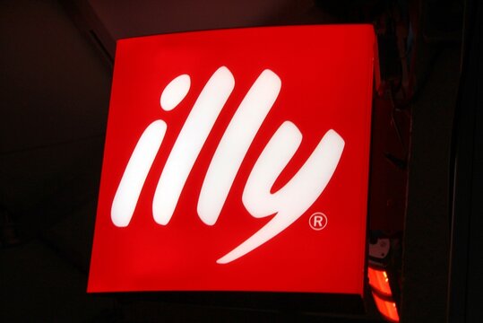 Kempten (Bayern), 27.12.2023, Deutschland: Beleuchteter Schriftzug und Logo von "illy" bei Nacht. Illycaffè ist ein italienisches Kaffeeunternehmen mit Sitz in Triest. 