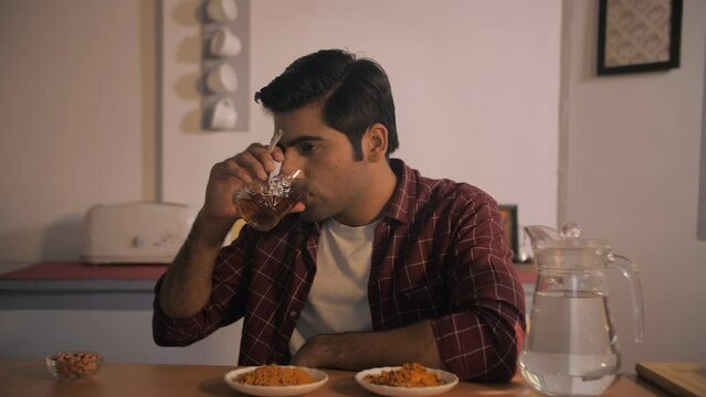 Depressed Indian male drinking and smoking - depression  stressful life  bad habit  substance abuse  alcoholic. Bachelor spending evening alone at home - abusing cigarettes and alcohol  chain smoki...