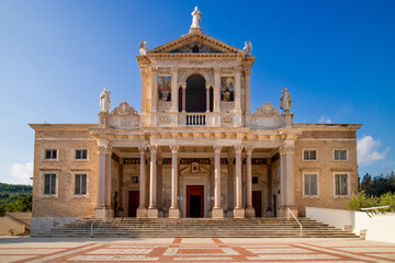Obraz premium Stunning church facade with ornate Corinthian columns, sacred statues, and vivid mosaics under a pristine blue sky