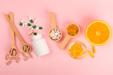 Vitamins and supplements. Variety of vitamin tablets in wooden spoons on a textured background....