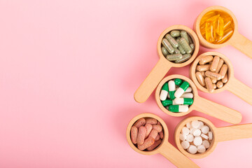 Vitamins and supplements. Variety of vitamin tablets in wooden spoons on a textured background. Multivitamin complex for every day. Nutritional supplements.Copy space.Vitamins for immunity