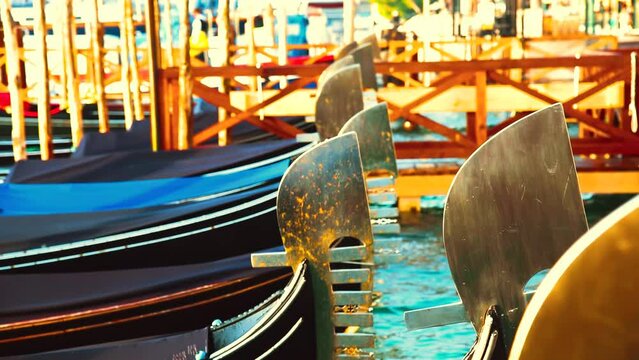 Venetian gondola nose ornaments close-up swinging on water in sunset 4k