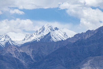 Fototapeta na wymiar A hazy shot of snow-capped Himalaya peaks with cloudy blue sky.