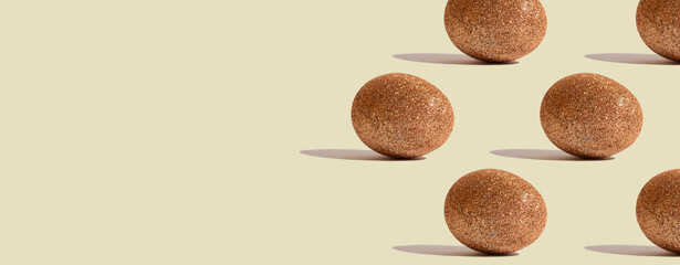Glitter gold eggs on beige background. Investment concept. Handmade decorated Easter eggs. Space for text. Banner or header