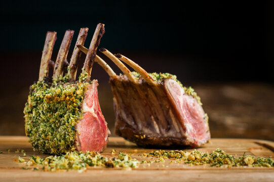 Rack of lamb with hazelnut herb crust on wooden board in restaurant