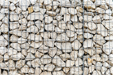 Traditional gabion wall made of rocks and metal grid as background. Stone wall with steel mesh as landscaping element. Building fence detail - obrazy, fototapety, plakaty