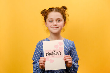 Portrait of happy adorable preteen girl kid holding card for Mother's Day with little pink hearts,...
