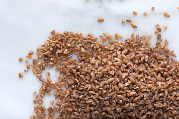 Close up of wheat grains on white marble background. Healthy food concept.