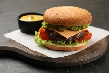 Tasty hamburger with patty and sauce on black table, closeup