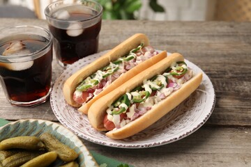 Delicious hot dogs with onion, chili pepper and sauce served on wooden table