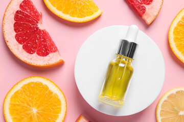 Bottle of cosmetic serum and citrus fruit slices on pink background, flat lay