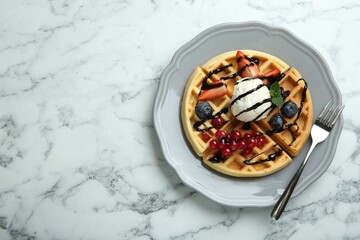 Delicious Belgian waffles with ice cream, berries and chocolate sauce on light marble table, top view. Space for text