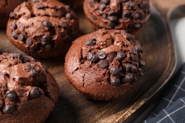 Tasty chocolate muffins on wooden serving board, closeup