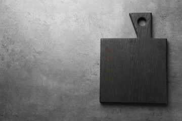 Black cutting board on grey table, top view. Space for text