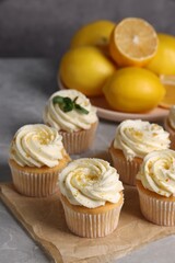 Delicious cupcakes with white cream and lemon zest on table, closeup