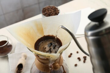 Making drip coffee. Pouring hot water into chemex coffeemaker with paper filter at table, closeup