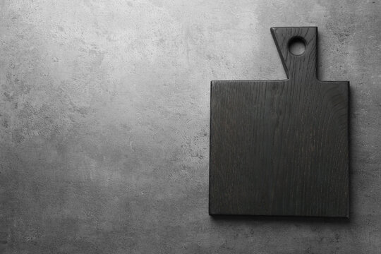 Black cutting board on grey table, top view. Space for text - Powered by Adobe
