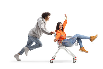 Guy running and pushing a happy young female inside a shopping cart