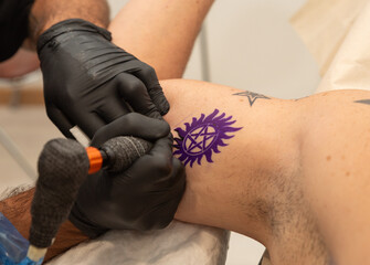 tattoo artist performing a tattoo on a client