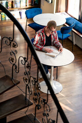male professor in glasses sits in a scientific and technical library reads a book and prepares to...
