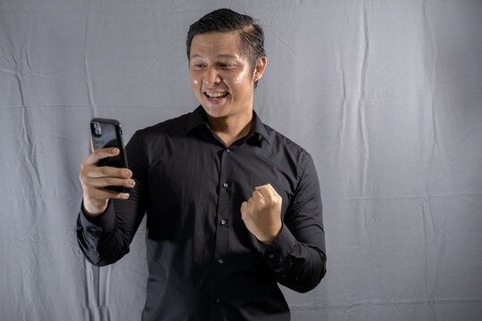 Young asian businessman looking at mobile phone with happy gesture