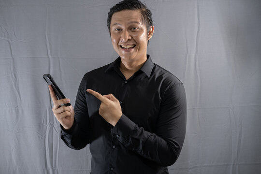 Young asian businessman looking at mobile phone with happy gesture