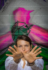 Portrait of a young woman with her face and her hands in front of a colorful painted background