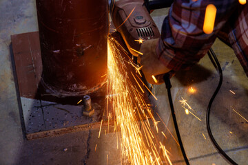 When grinding iron with spark an abrasive disk in industrial factory worker uses to cut metal