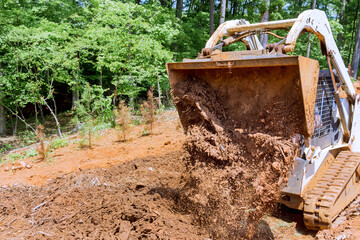 Working with earth with mini bulldozer moving soil for landscaping purposes enhancing property