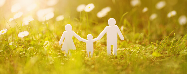 Figurines of family standing on the fields with white daisies on sunset.