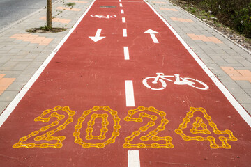 Red Bike Trail in city with 2024 Happy New Year made from golden chain links