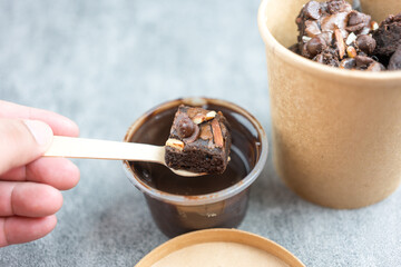 Delicious chocolate brownie with almond slices topping doing dipping melted chocolate
