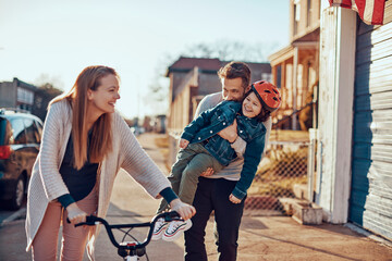 Fototapeta premium Boy learning to ride a bike with supportive parents