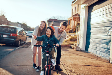 Boy learning to ride a bike with supportive parents