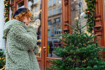 young woman choosing Christmas tree at Christmas tree market